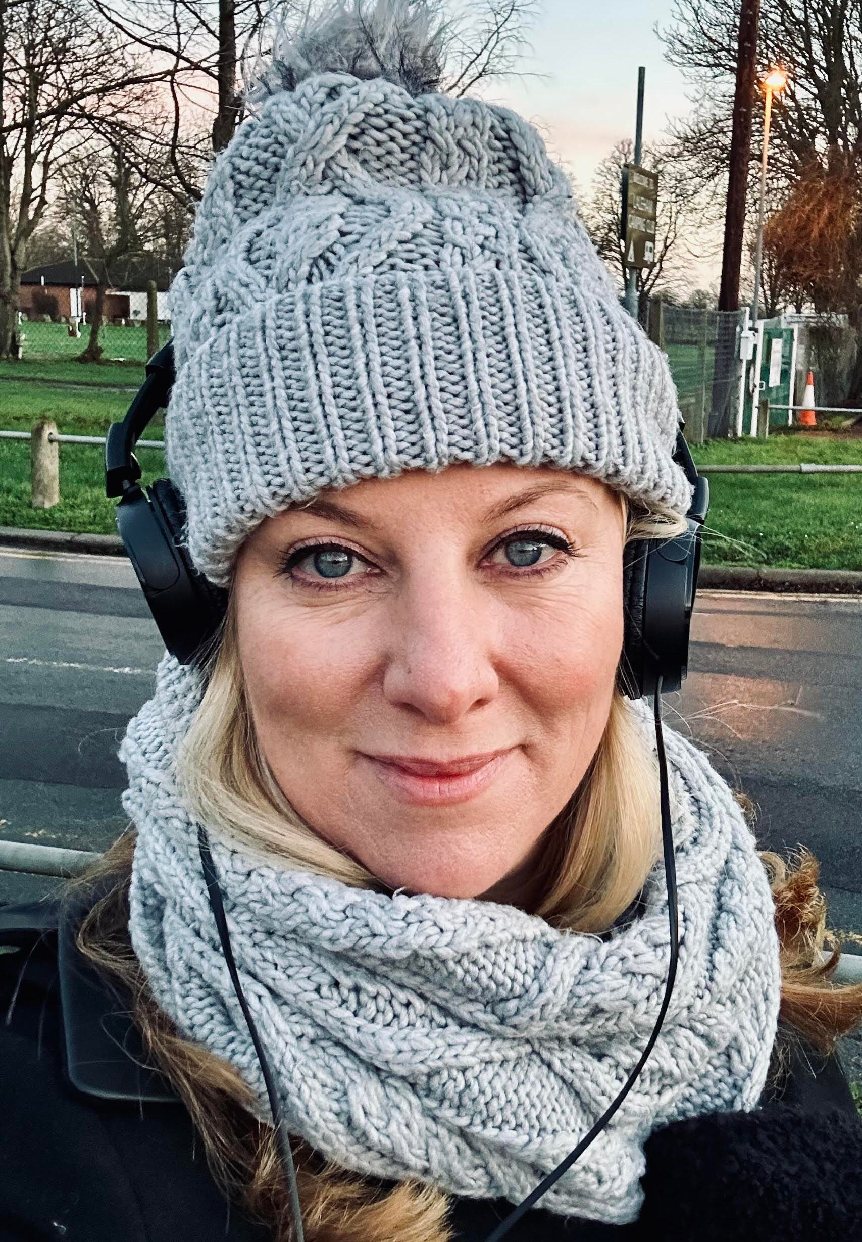 Sara Thornton wearing a grey knit hat and scarf with headphones.
